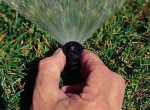 a Redmond Sprinkler Repair tech adjusts a pop up head by hand